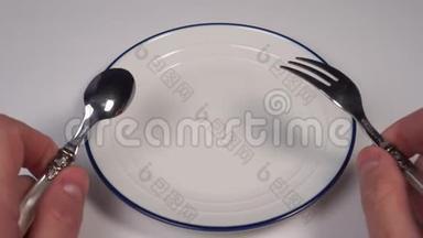 空的白色盘子，在餐馆的桌子上有一个蓝色的<strong>边框</strong>。 在<strong>甜点</strong>叉子和勺子的手里